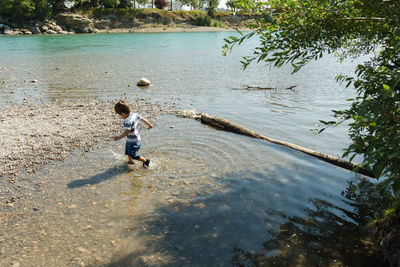 Rear view of boy standing in lake