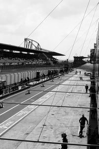 People walking on bridge in city against sky