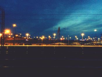 Illuminated road in city against sky at night