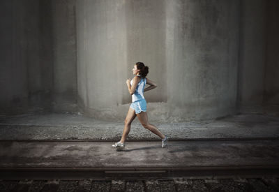 Determined female athlete jogging on footpath by railroad track