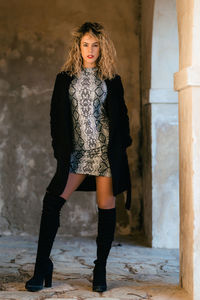 Full length portrait of woman standing by wall