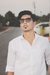 Portrait of young man wearing sunglasses standing outdoors