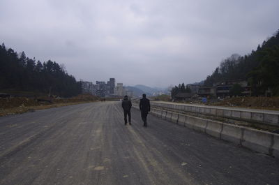 Rear view of people walking on road in city