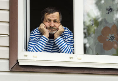 Portrait of man looking through window