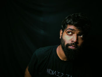 Portrait of young man against black background