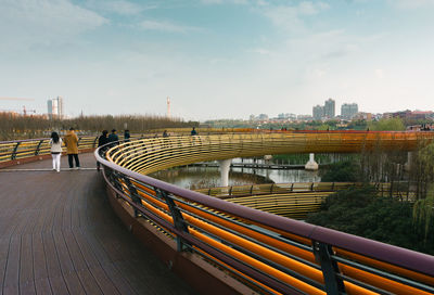 Footbridge over river in city against sky