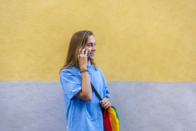 Man talking on the phone while wearing a belt bag with the lgbt rainbow flag.