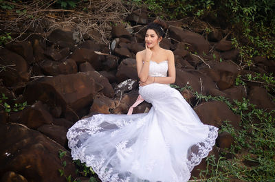 Full length of bride sitting on rock