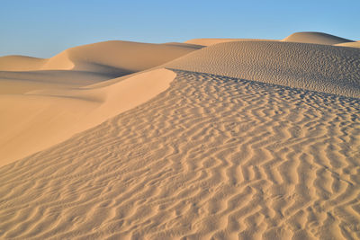 Sand dune in desert against clear sky