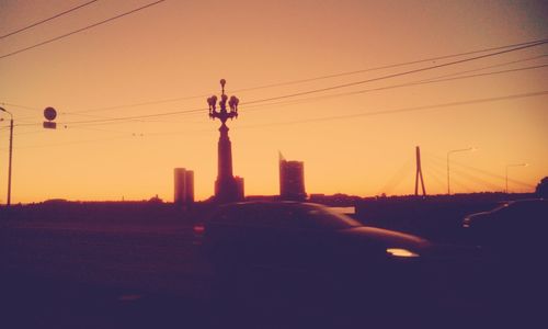 Silhouette of electricity pylon against sky at sunset