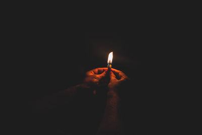 Close-up of hand holding illuminated light over black background