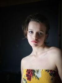 Portrait of girl standing against black background