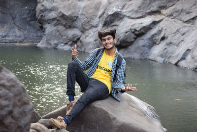 Portrait of smiling man sitting on rock