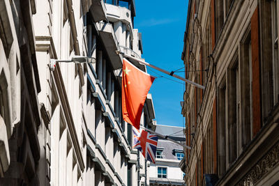  low angle view of chinese and uk flag in the city of london. concept international commerce