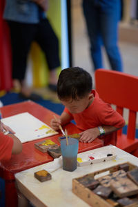 High angle view of boy painting on table