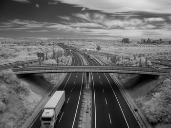 Infrared image of bridge over road against cloudy sky