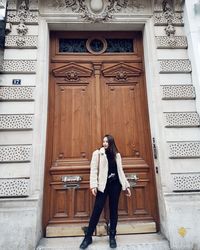 Full length of woman standing against door