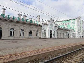 Railroad station platform by city against sky