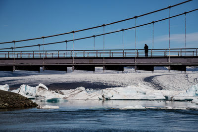 Bridge over river against clear sky during winter