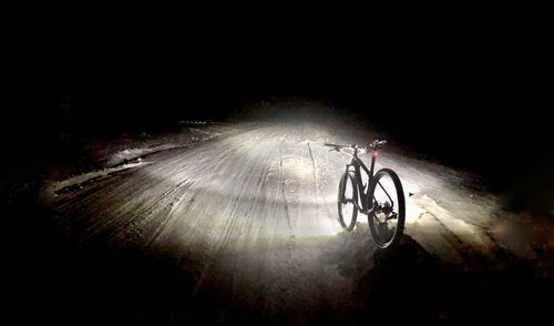 Bicycle parked on road at night