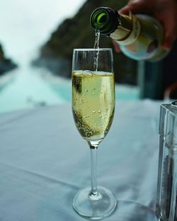 Cropped image of hand pouring champagne in flute on table at restaurant