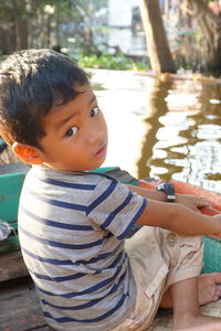 Portrait of cute boy sitting on boat in lake 