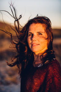 Portrait of beautiful young woman standing against sky during sunset