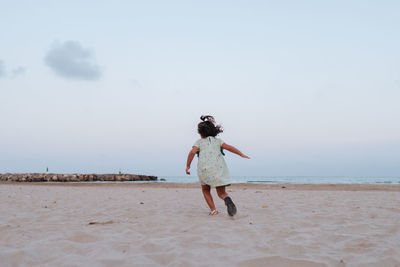 Little girl running on the sand of the beach in the blue hour