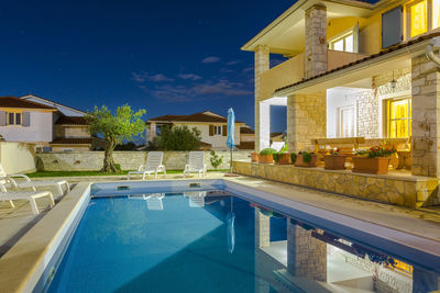 Swimming pool by building against blue sky