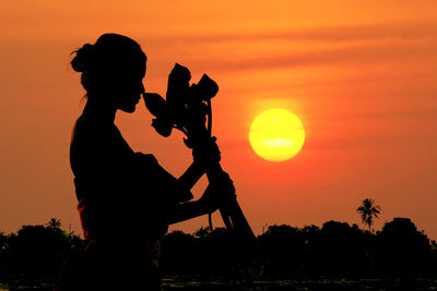 Silhouette people against orange sky during sunset