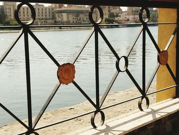 Close-up of heart shape hanging on railing by river