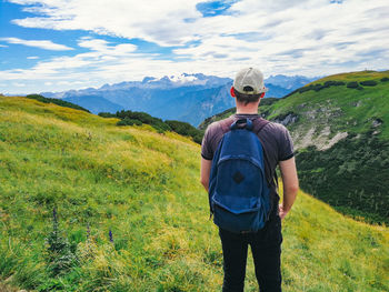 Rear view of man standing on mountain against sky