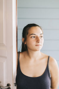 Thoughtful young woman standing by door