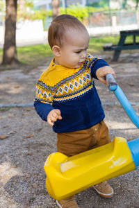 Cute baby boy having fun on outdoor playground. toddler activities. serious baby swinging on swing.