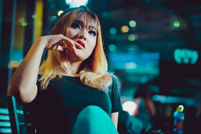 Beautiful young woman sitting outdoors at night