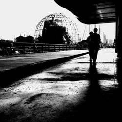 Rear view of silhouette woman walking on bridge