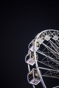 Low angle view of illuminated ferris wheel against black background