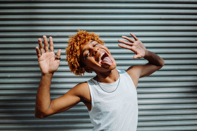 Stylish teenager with curly hair and makeup dancing hip-hop on the street