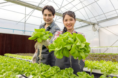 Portrait of a smiling young woman standing in greenhouse