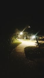 Illuminated road against sky at night