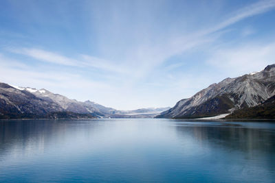 Scenic view of lake and rocky mountains against cloudy sky