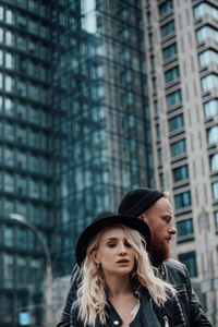 Portrait of happy young woman against building in city