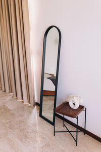 Mirror and side table in front of a white wall,