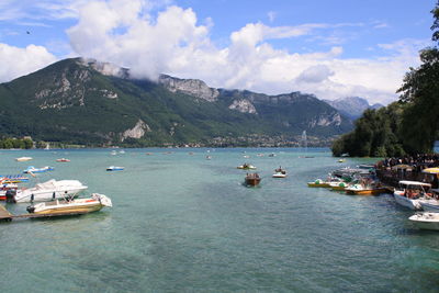 Boats moored on sea by mountains against sky