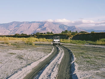 Road by mountains against sky