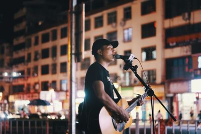 Side view of man playing guitar in city