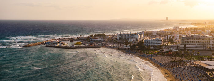 High angle view of townscape by sea against sky during sunset