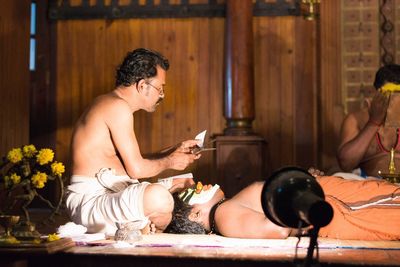Man holding mobile phone while sitting on laptop