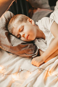 Portrait of a boy sleeping under a white blanket and with a garland. christmas night baby