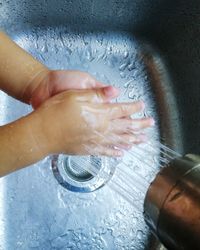 High angle view of woman hand holding wet glass